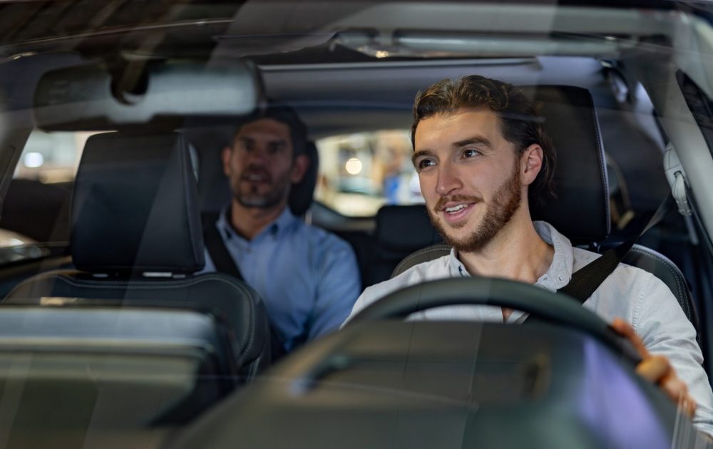 Latin American crowdsourced taxi driver taking to a passenger in the back seat - mobility as a service concepts
